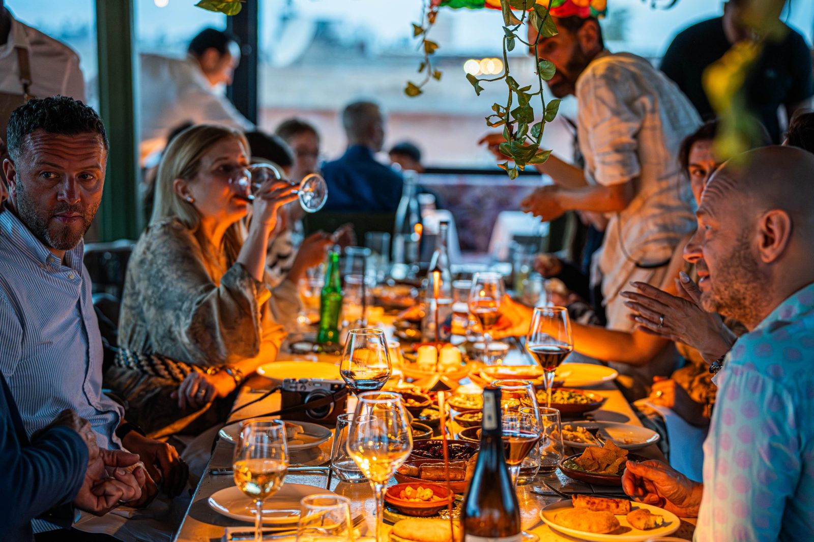 Friends sharing a long candlelit dinner on a restaurant terrace